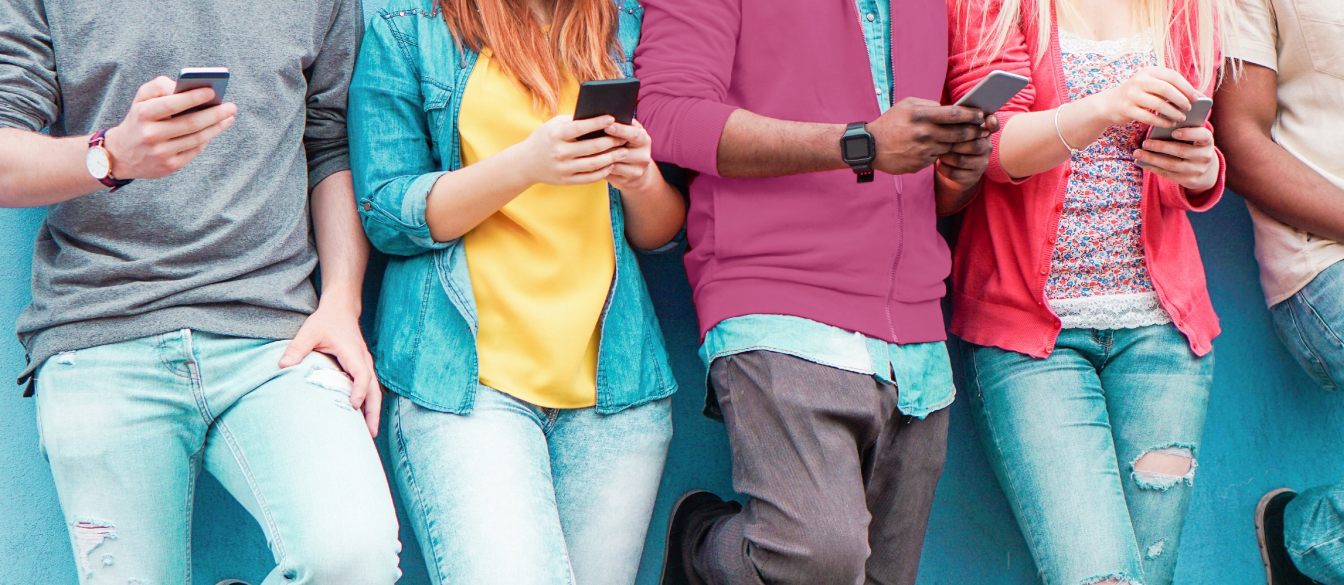 A group of people standing in a row, each looking at their phones.