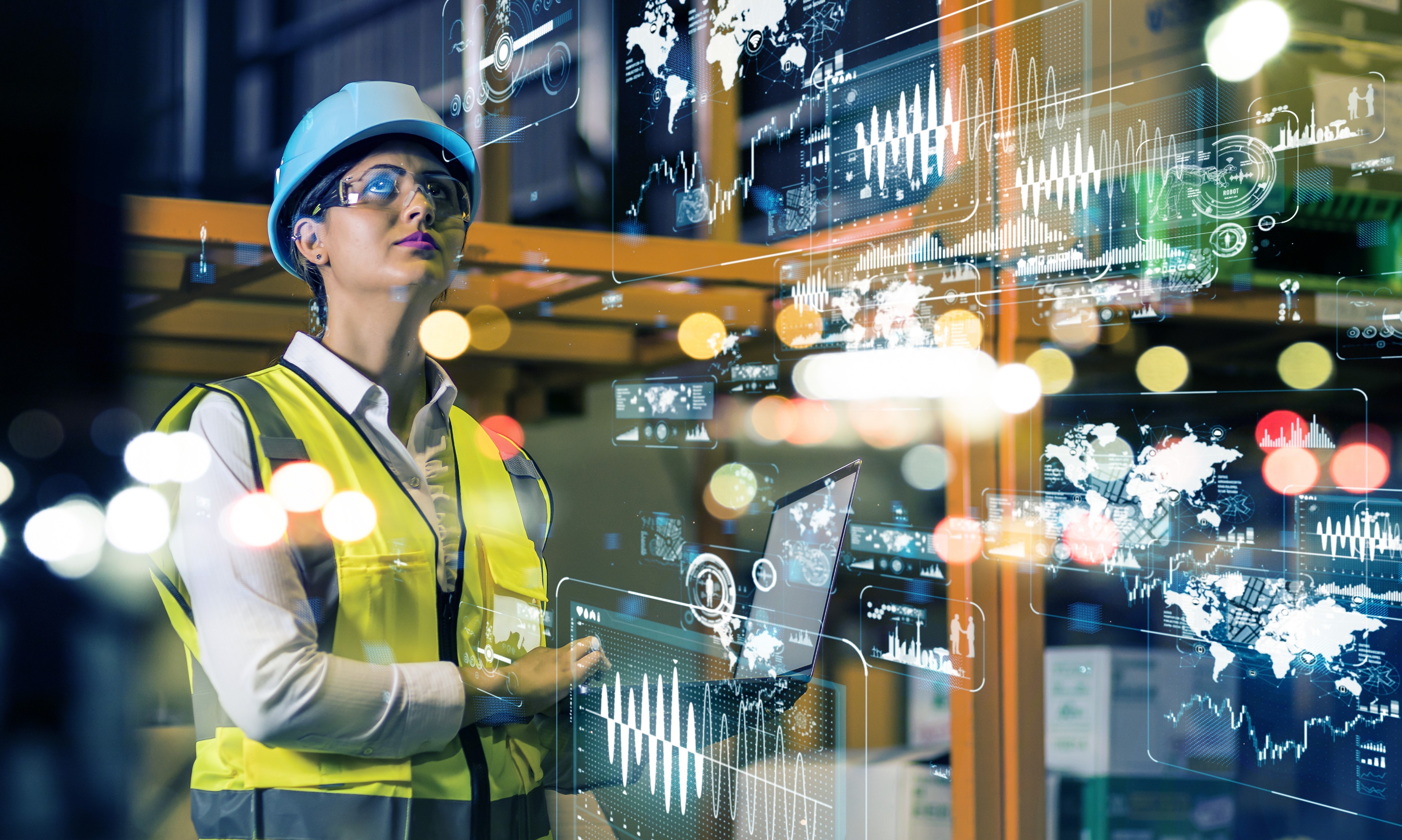 A woman wearing a hard hat and safety vest in an industrial setting, with digital data and graphs overlayed in the foreground.